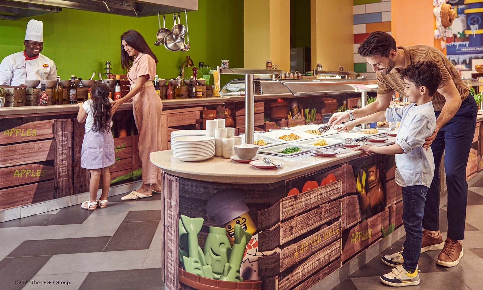 In a vibrant restaurant, a chef smiles at a woman and child selecting food
