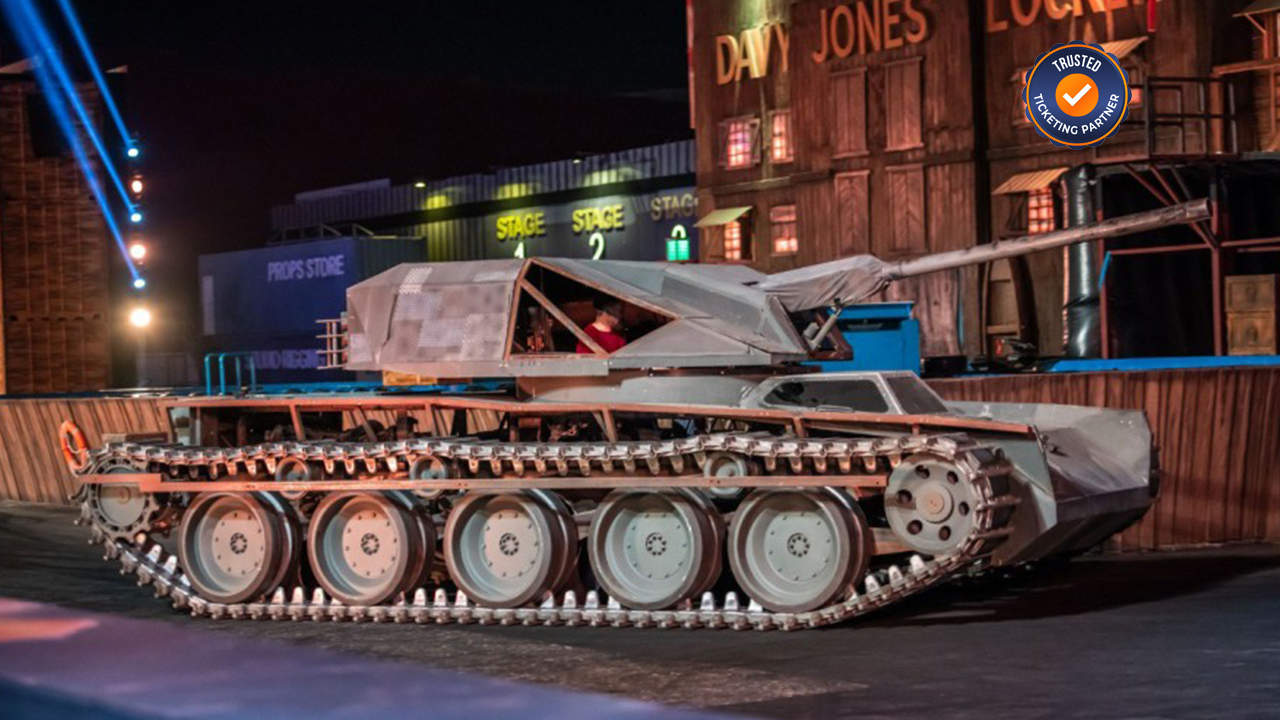 Stage set with realistic military tank on tracks, illuminated under colorful lights.